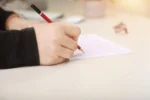 a hand holding a pen and writing on a piece of paper